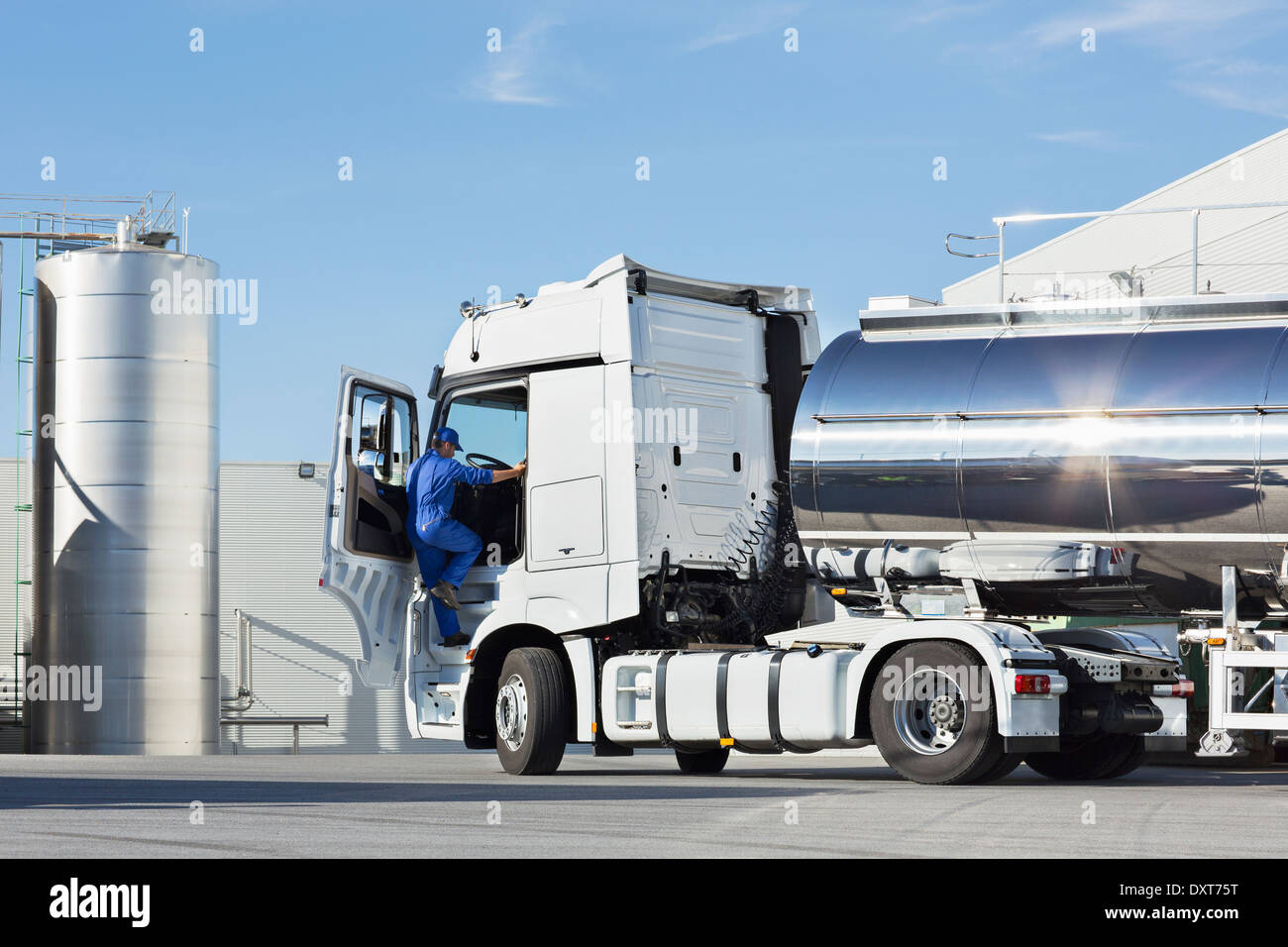 Truck driver climbing into stainless steel milk tanker Stock Photo