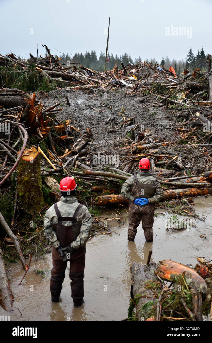 Rescue workers stand for a moment of silence in honor of the victims of a massive landslide that killed at least 28 people and destroyed a small riverside village in northwestern Washington state March 30, 2014 in Oso, Washington. Stock Photo