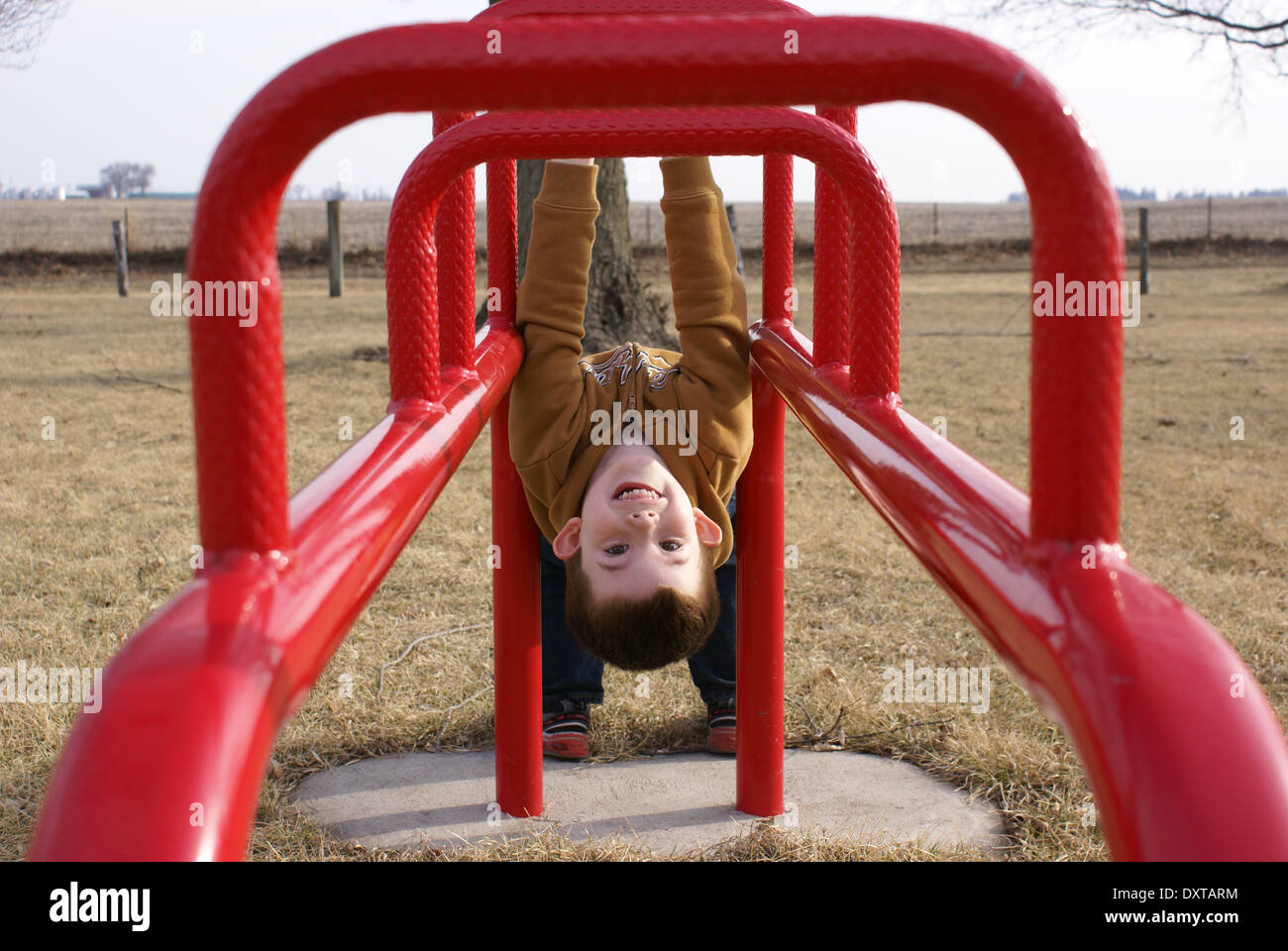 Little boy hanging upside down on playground equipment Stock Photo Alamy