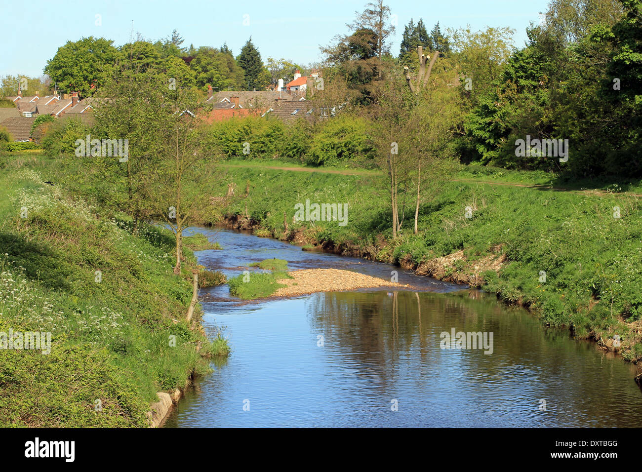 Scenic view of river in countryside with village houses in background. Stock Photo