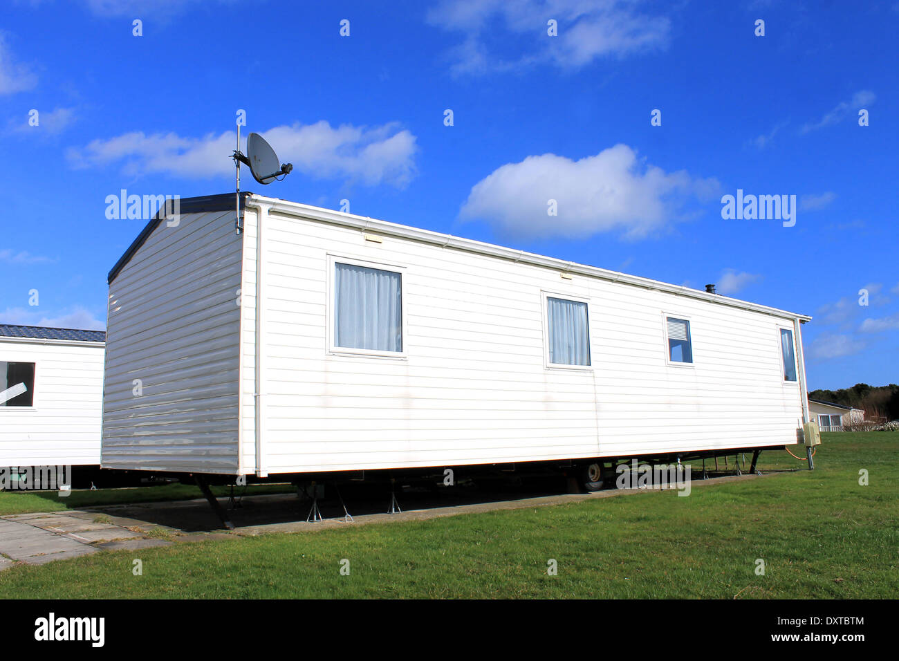 Side view of trailer on caravan park with blue sky and cloudscape background. Stock Photo
