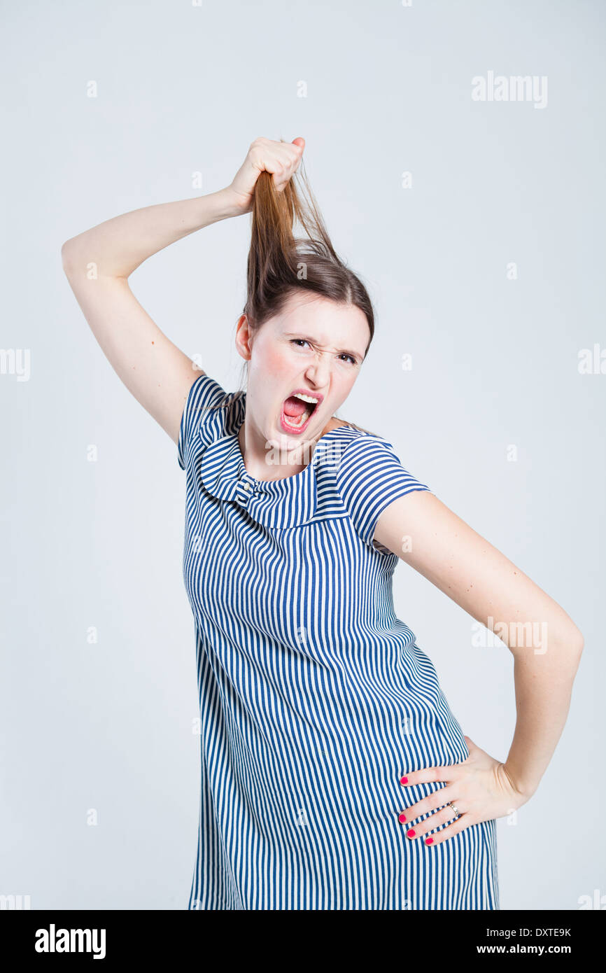 Studio portrait of attractive and stylish woman playfully pulling her hair while shouting Stock Photo