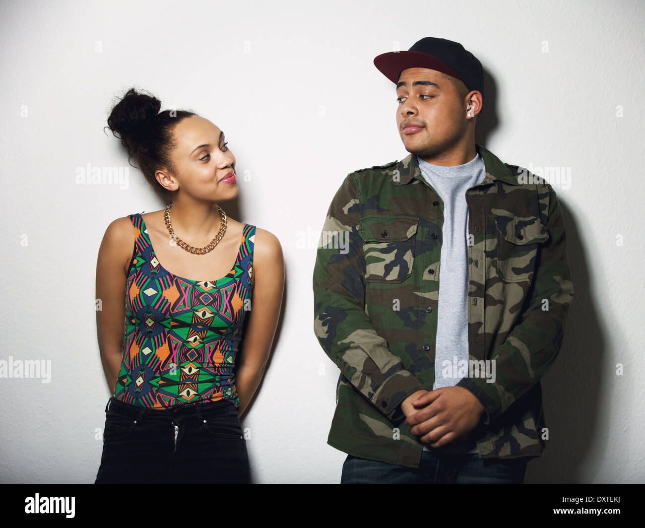 Young man and woman looking at each other with attitude. Young couple in casual wear on gray background. Stock Photo