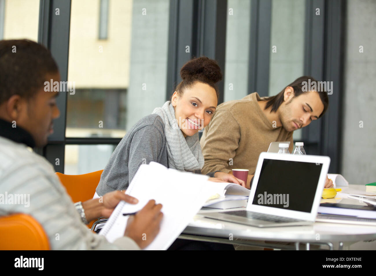 Cheerful young woman looking at camera while studying. university students studying with books and laptop in library. Stock Photo