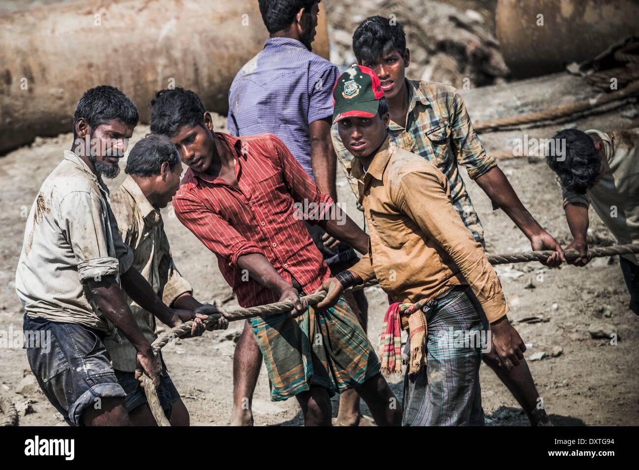 Workers are dragging a heavy pull rope in a shipbreaking yard in Chittagong. Once the beach at the shipwrecking places in Chittagong, Bangladesh were white and clean. Today Chittagong is partially soaked with oil and toxic mud. Chittagong is one of the wor Stock Photo