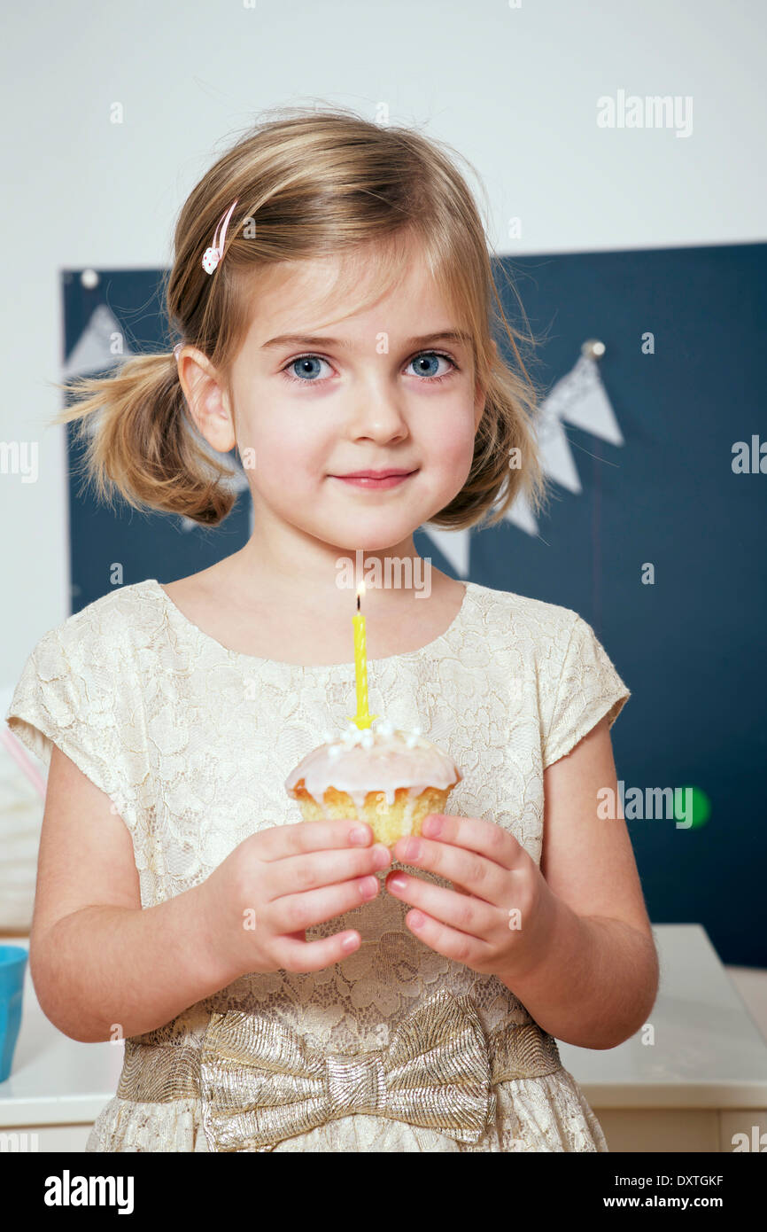 Girl on birthday party holding cupcake wit burning candle, Munich, Bavaria, Germany Stock Photo
