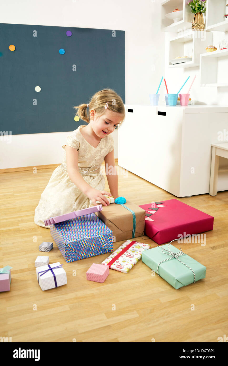 Girl on birthday party unwrapping gift boxes, Munich, Bavaria, Germany