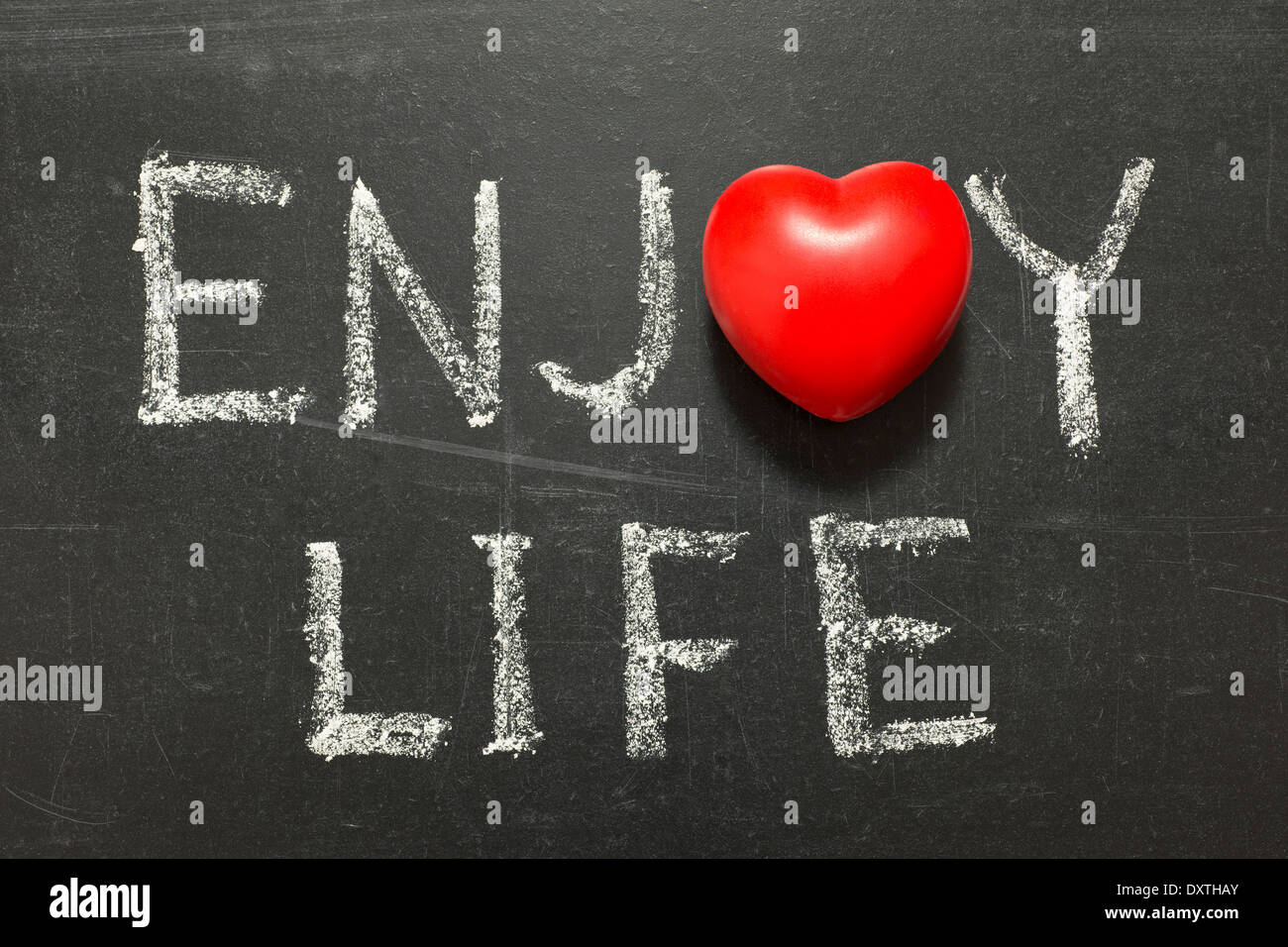 enjoy life phrase handwritten on chalkboard with heart symbol instead of O Stock Photo