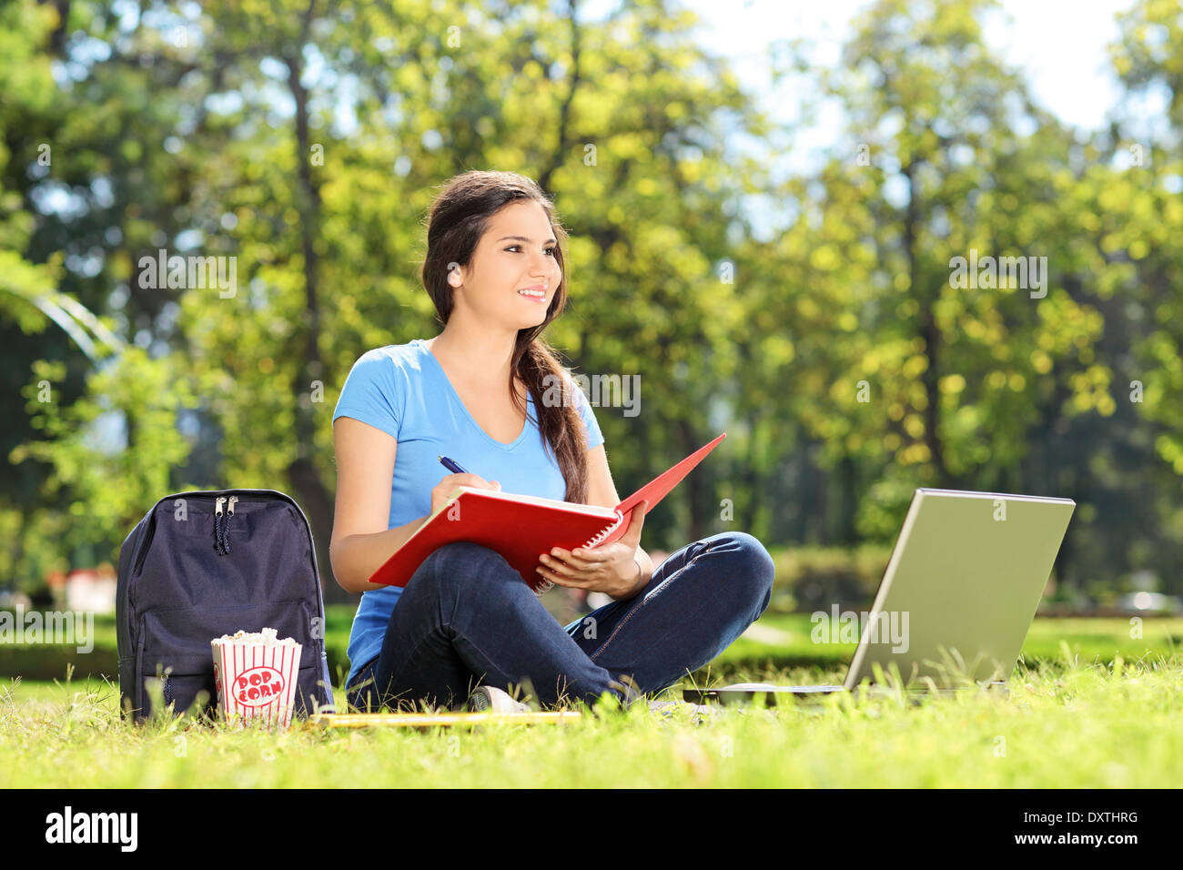 Young girl sitting in park and writing in notebook Stock Photo - Alamy