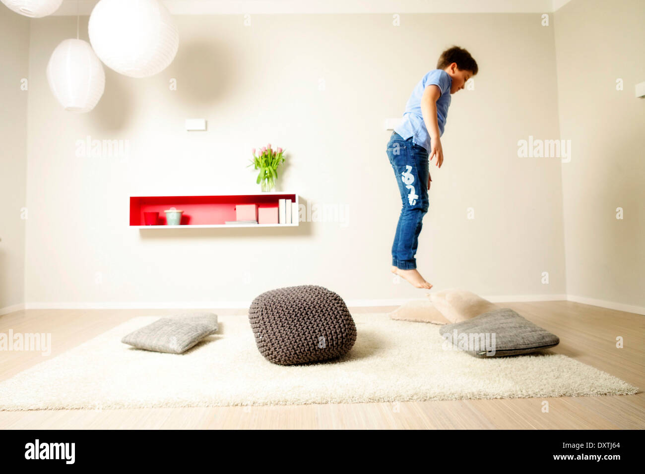 Boy jumping across cushions, having fun, Munich, Bavaria, Germany Stock Photo