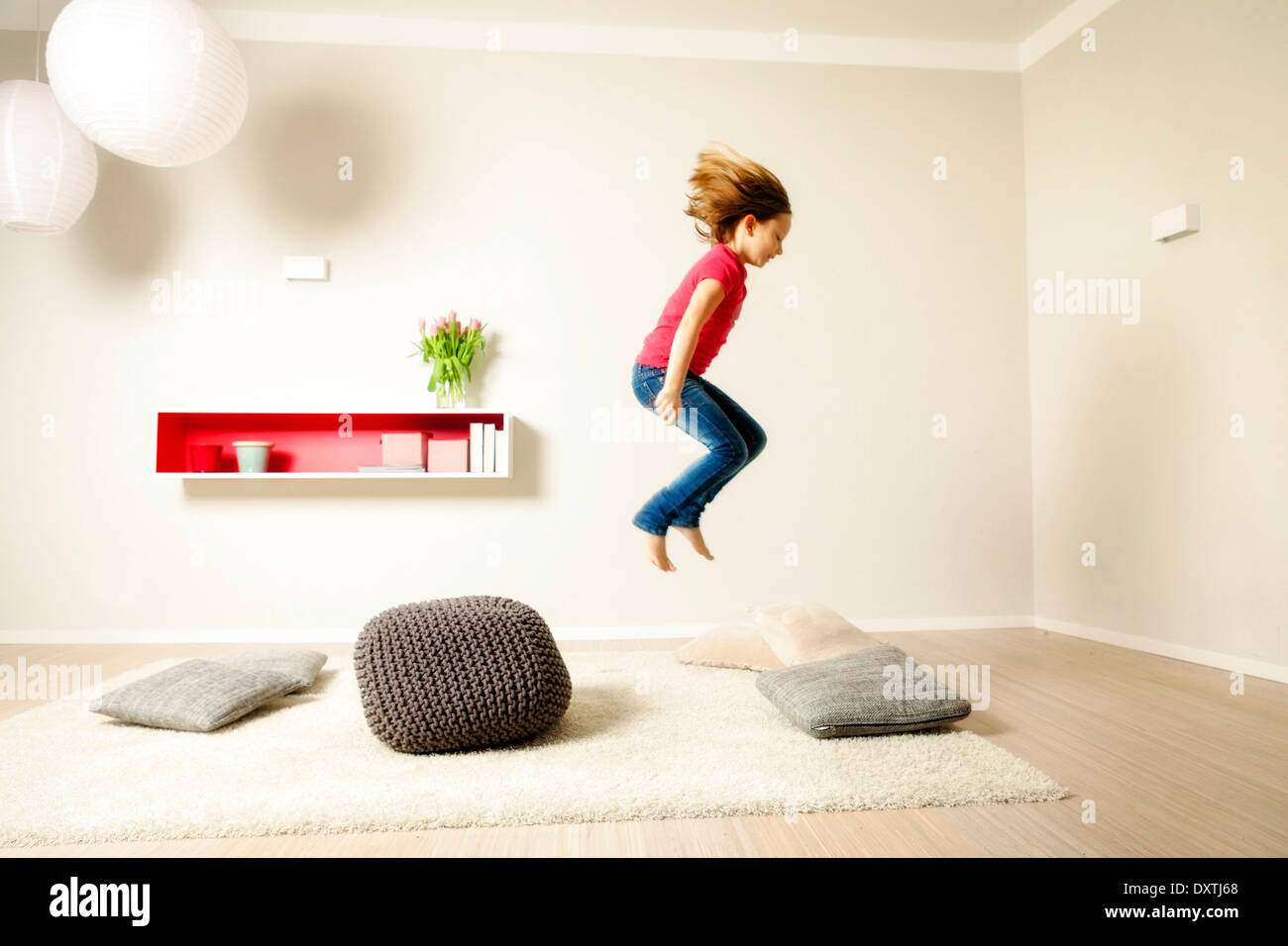 Girl jumping across cushions, having fun, Munich, Bavaria, Germany Stock Photo