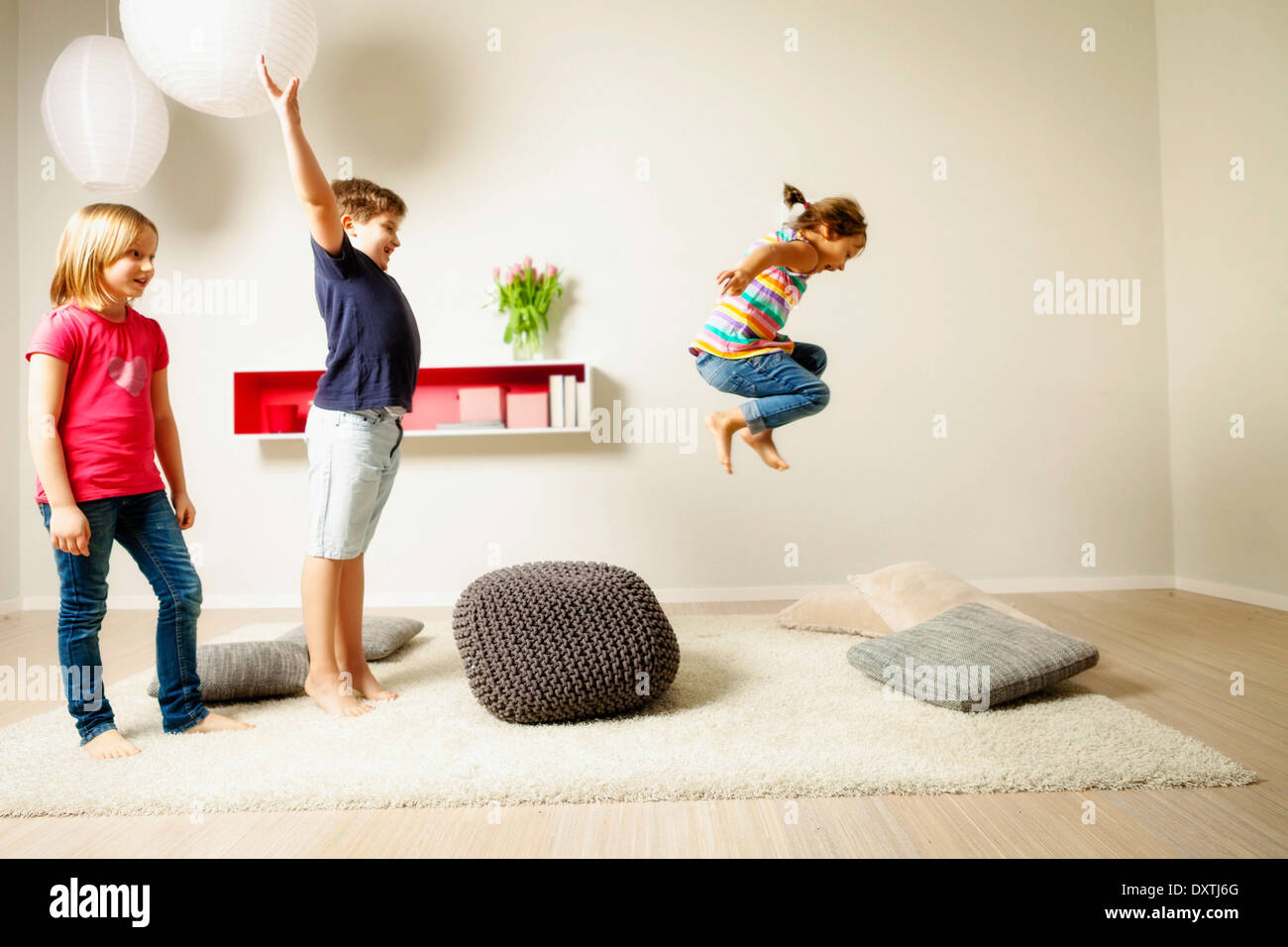Children in living room jumping across cushions, Munich, Bavaria, Germany Stock Photo