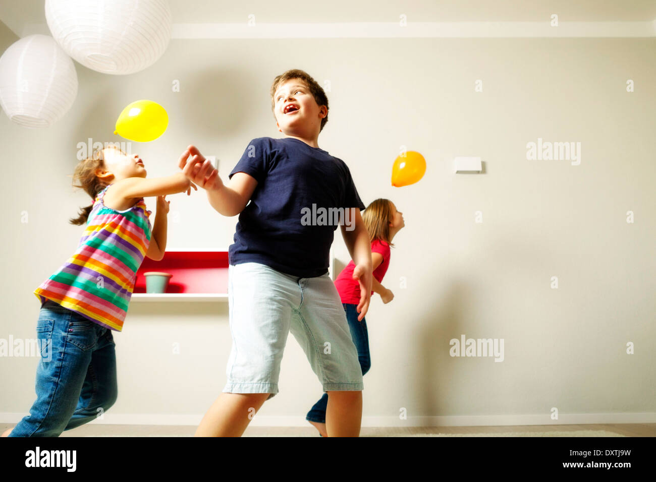 Children in living room playing with balloons, Munich, Bavaria, Germany Stock Photo