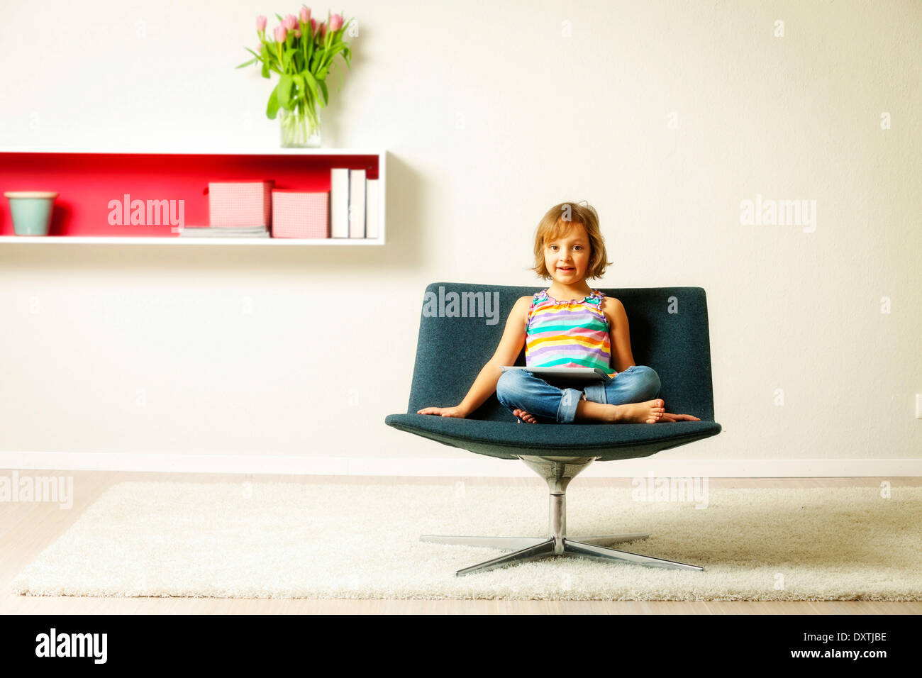 Girl sits in chair using tablet computer, Munich, Bavaria, Germany Stock Photo