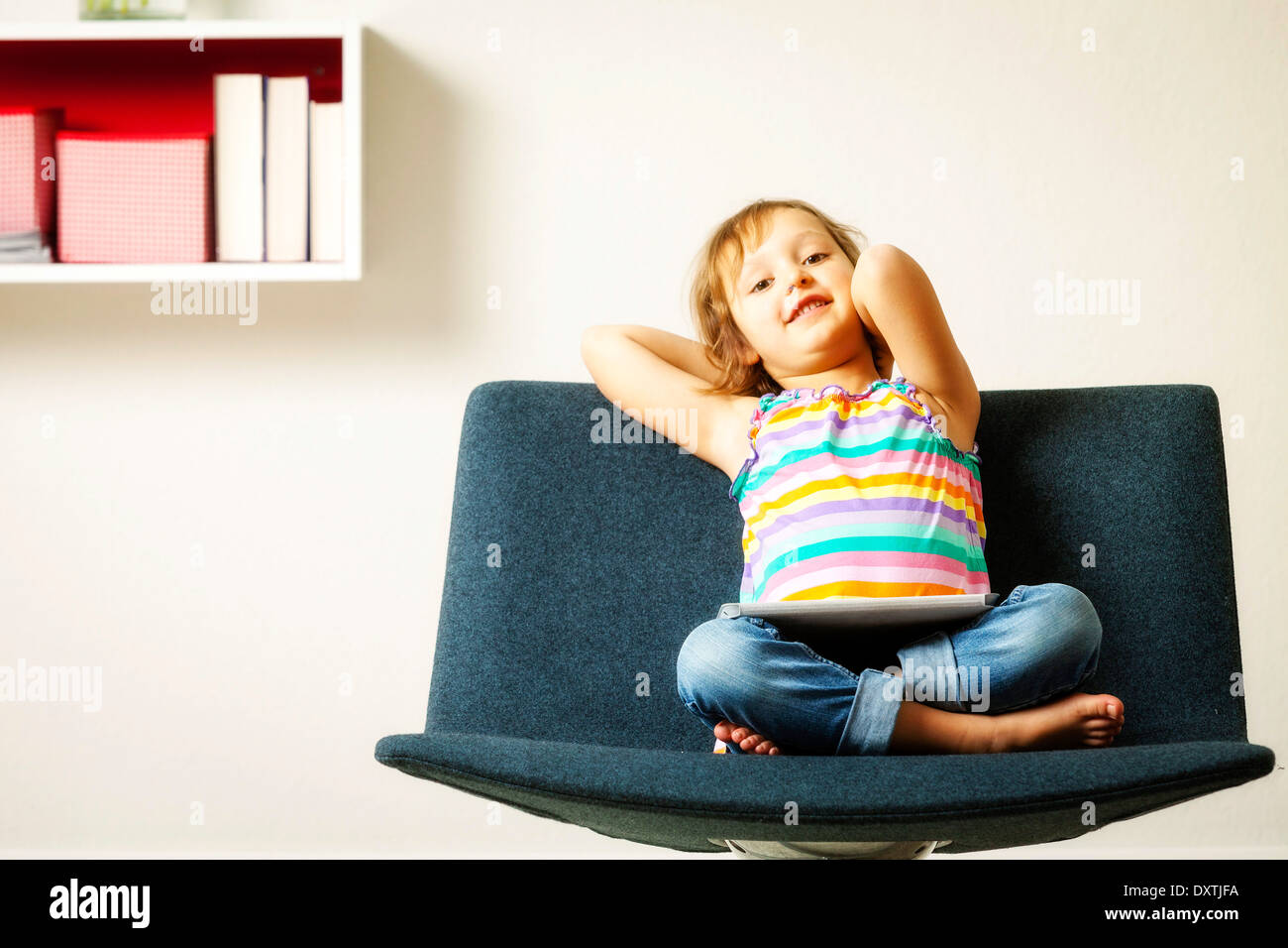Girl sits in chair using tablet computer, Munich, Bavaria, Germany Stock Photo