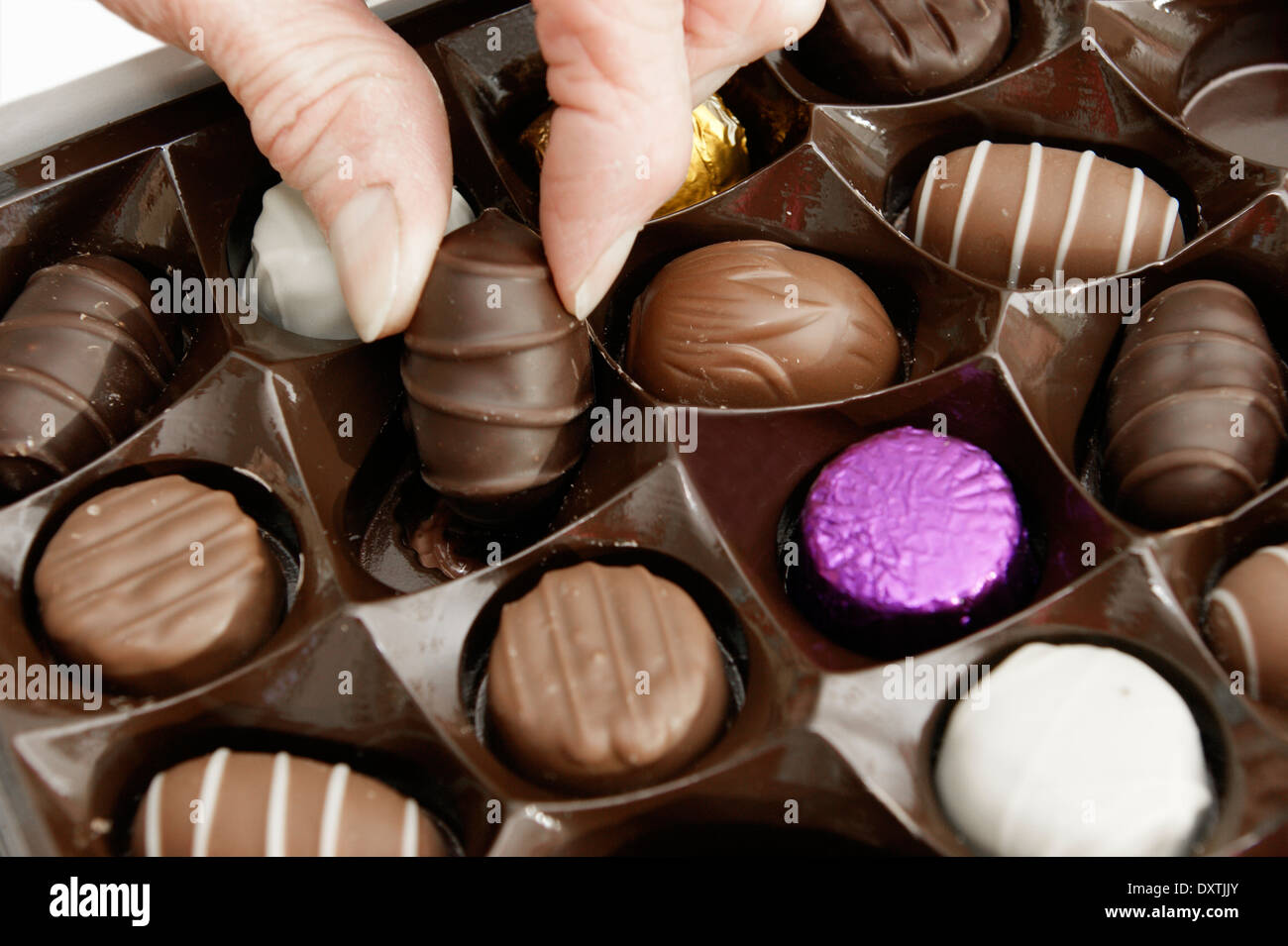 Woman helping herself to a chocolate from a box of chocolates Stock Photo