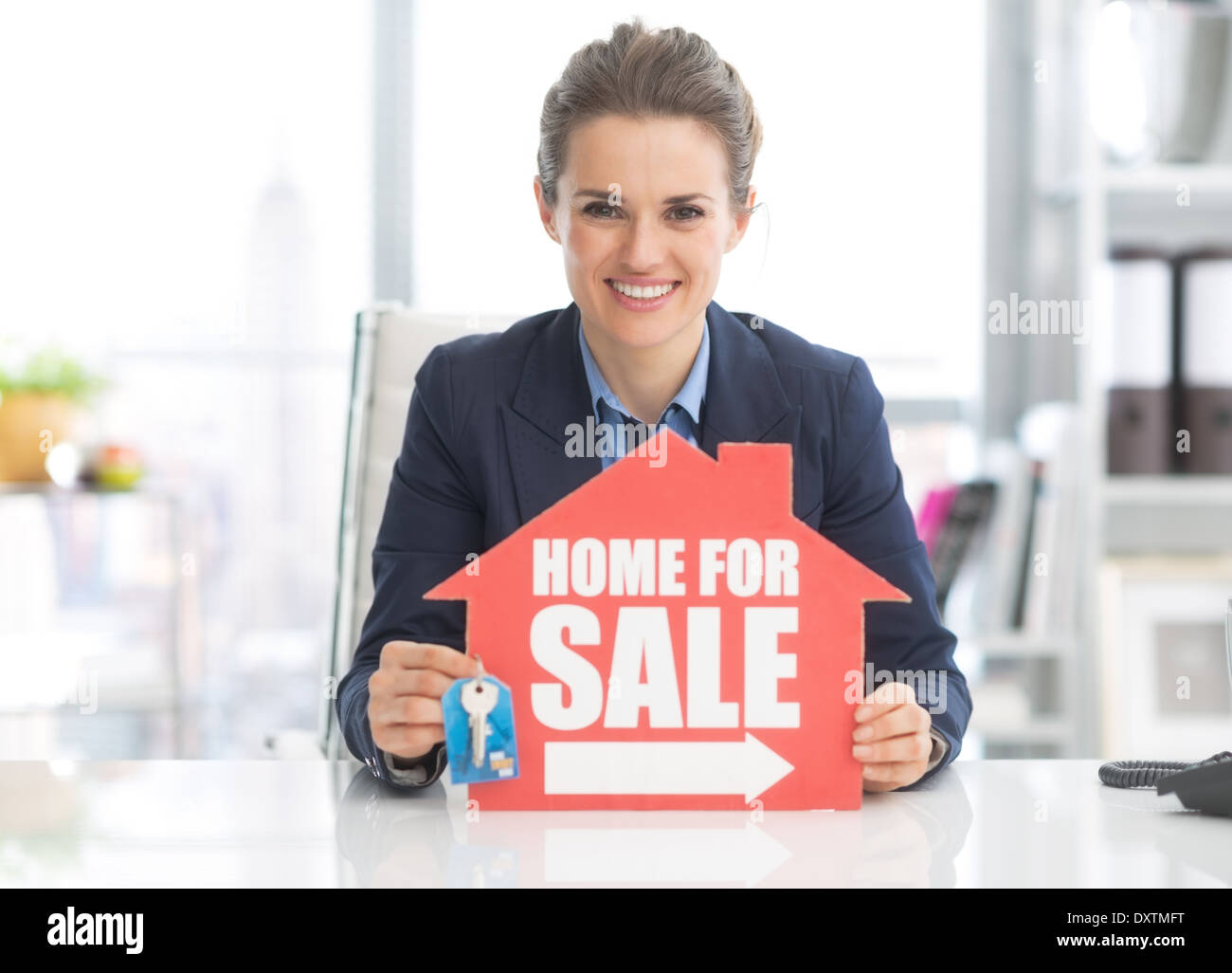 Realtor woman showing keys and home for sale sign Stock Photo - Alamy