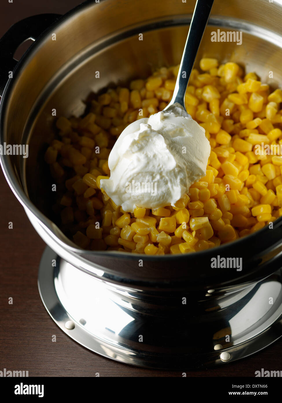 Adding the thick cream to the sweetcorn for Chinese patés Stock Photo