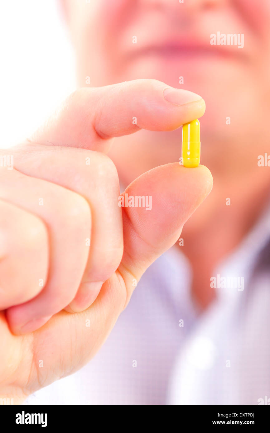 Senior adult man holds medicine capsule in his hand Stock Photo