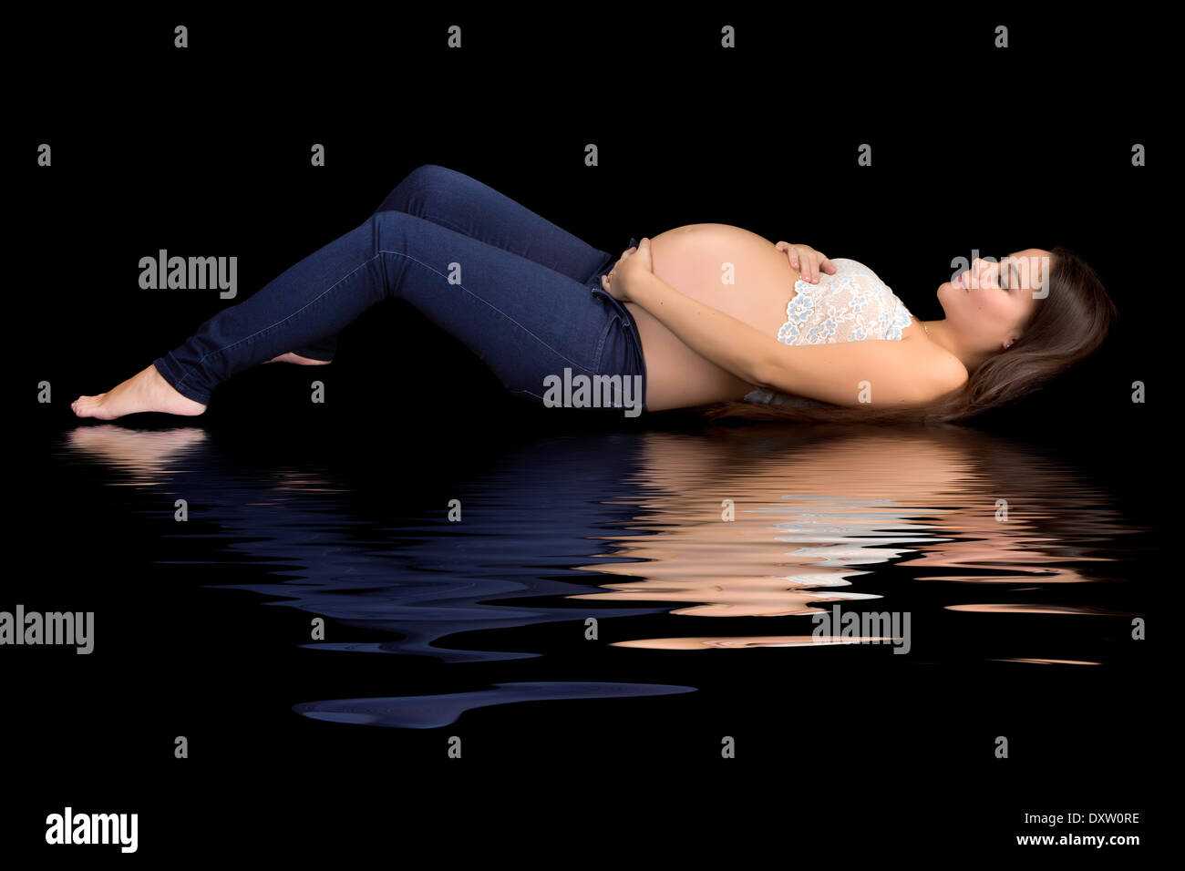 Attractive young pregnant woman reflected on a black background Stock Photo