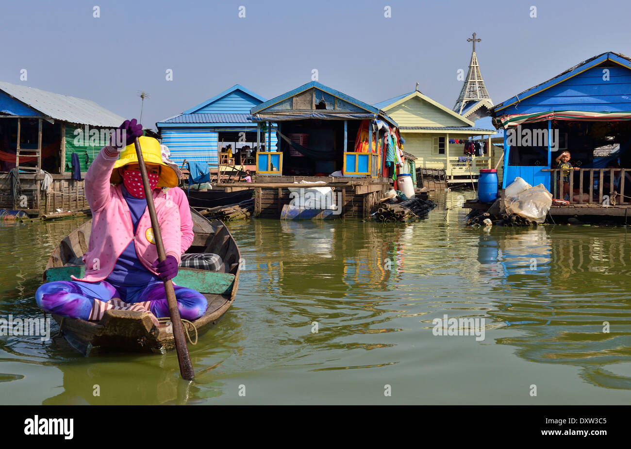 Cambodian woman paddling her wooden boat in front of the floating houses and houseboats on Tonle Sap lake, between Battambang & Siem Reap, Cambodia Stock Photo