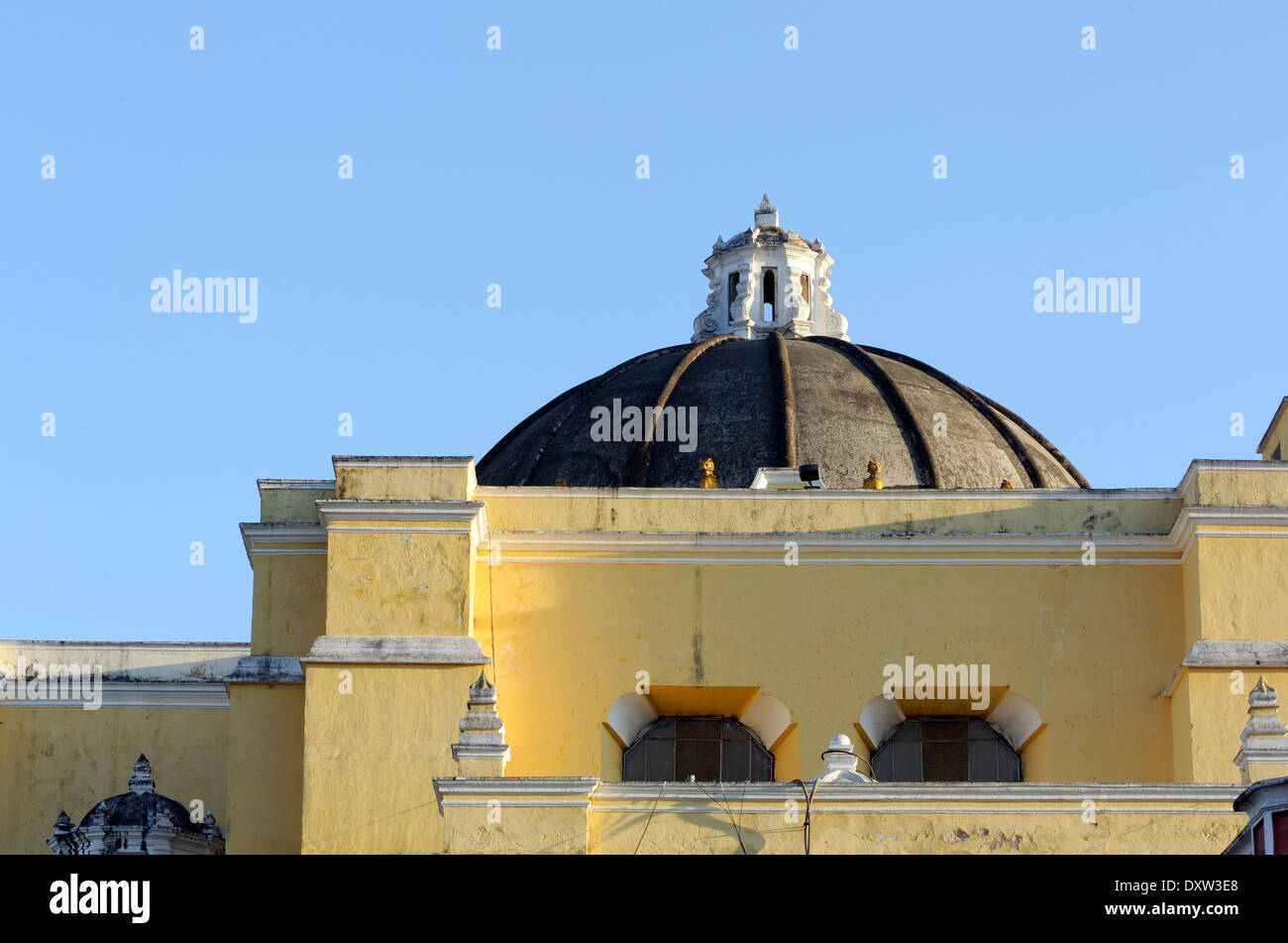 A cyclist travels over the cobbles of up 5 Avenida Norte if front of the dome of  the church of  La Merced.  Antigua Guatemala, Stock Photo
