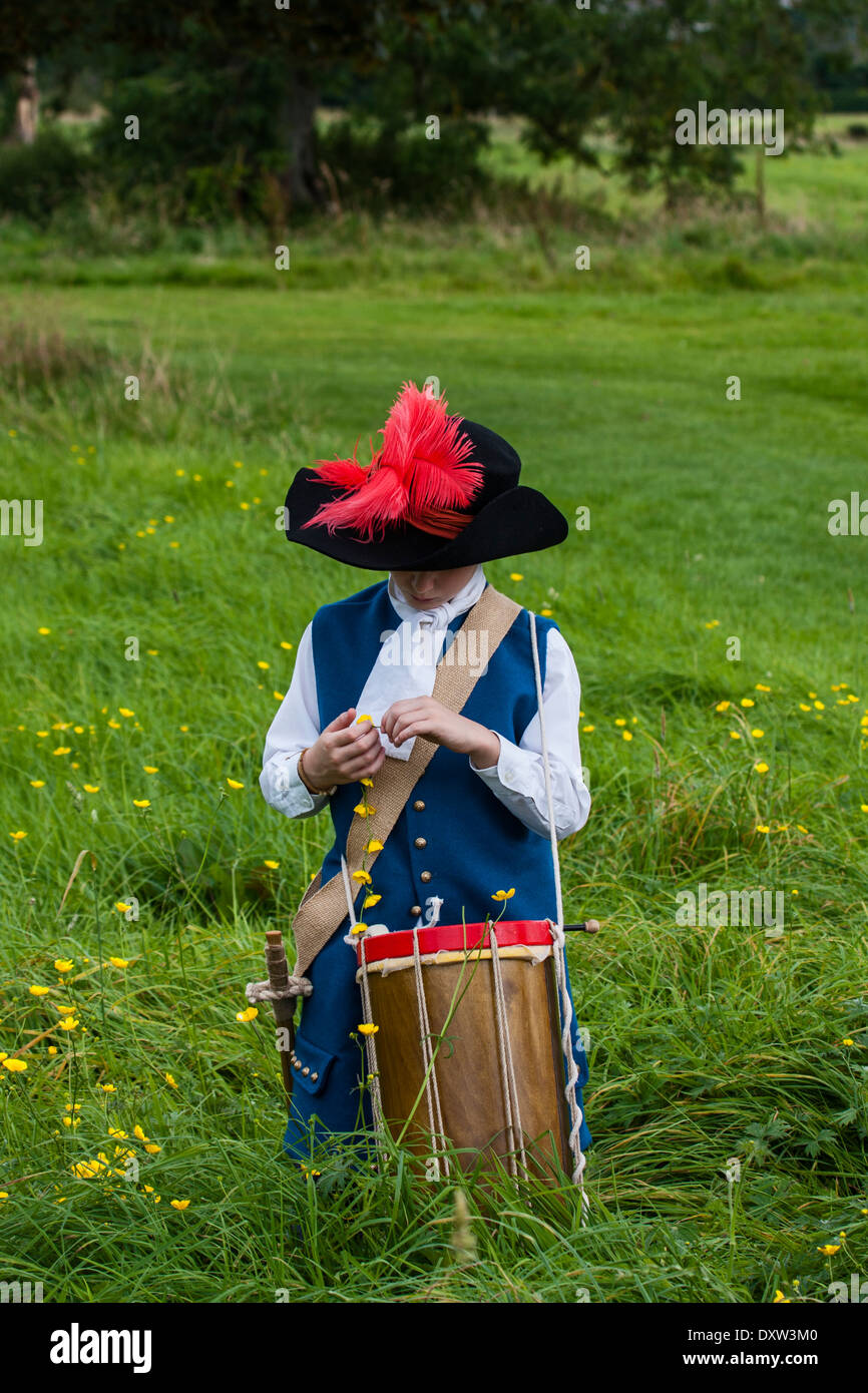 Drogheda, Louth, Ireland, Drummer Boy dressed in period costume making buttercup chains at Oldbridge Estate Drogheda Stock Photo