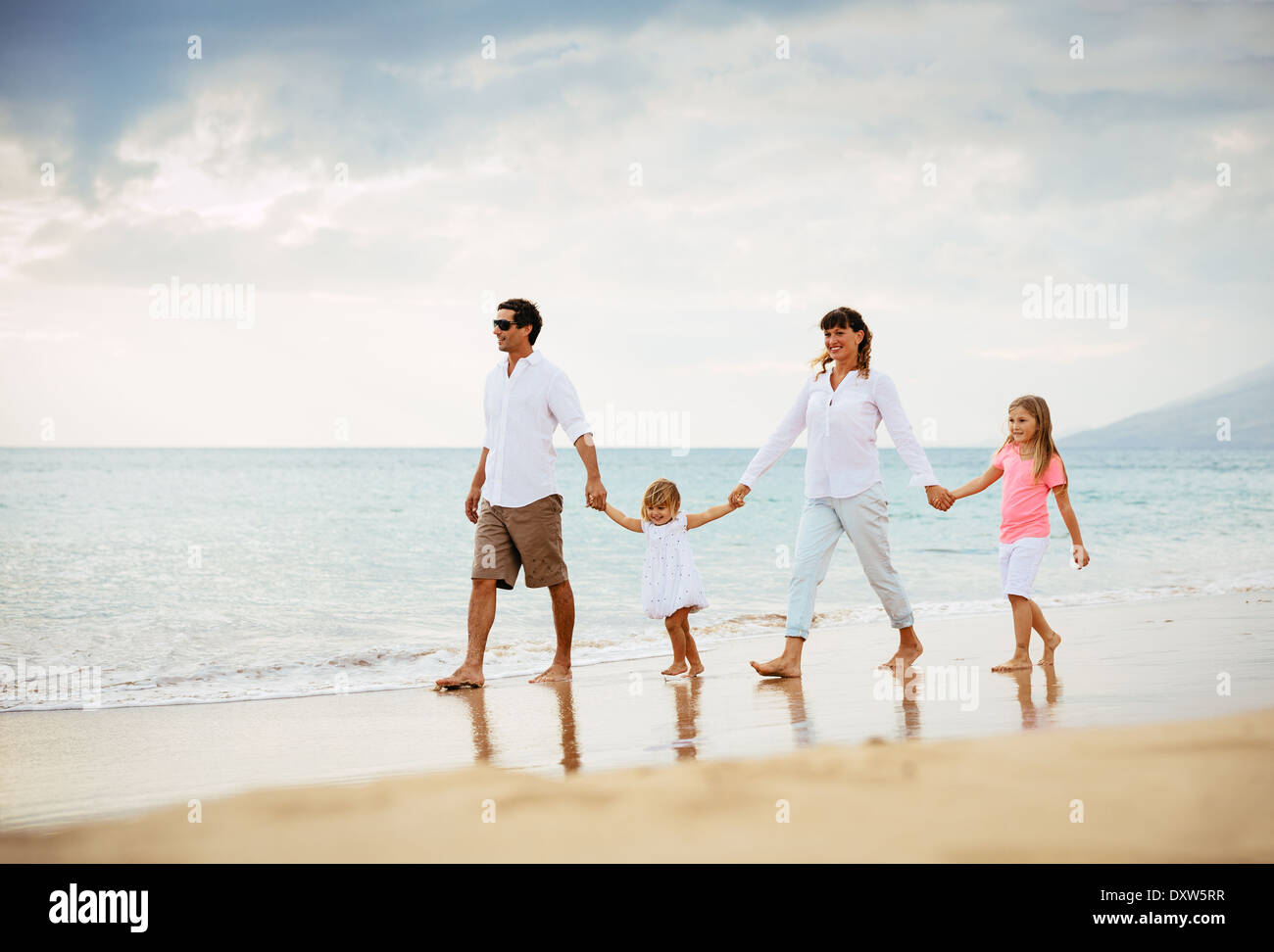 Happy Young Family have Fun Walking on Beach at Sunset Stock Photo