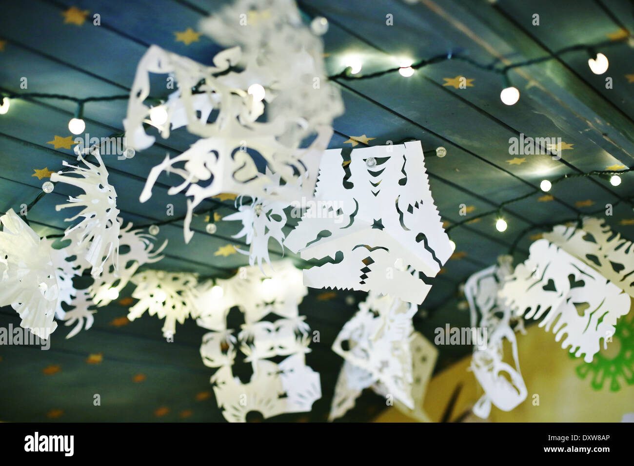 Paper Snowflakes Hanging On A Ceiling With Twinkly Lights Stock