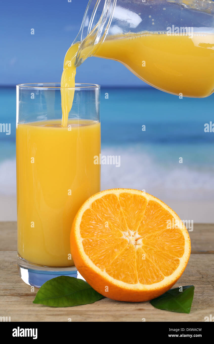 Orange juice pouring into a glass on the beach while on vacation Stock Photo