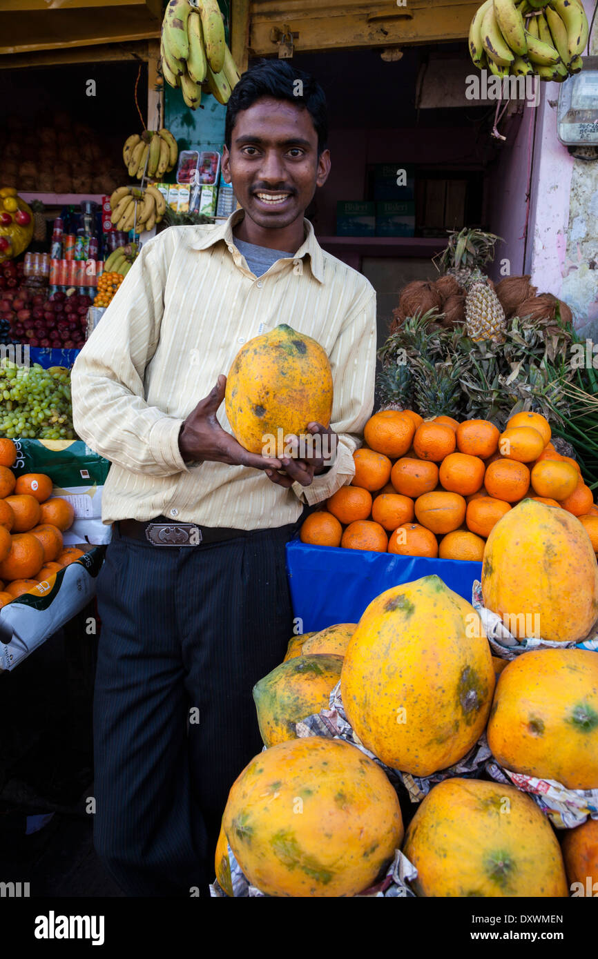 India, Dehradun. Fruit and Vegetable Vendor Holding a Papaya in a