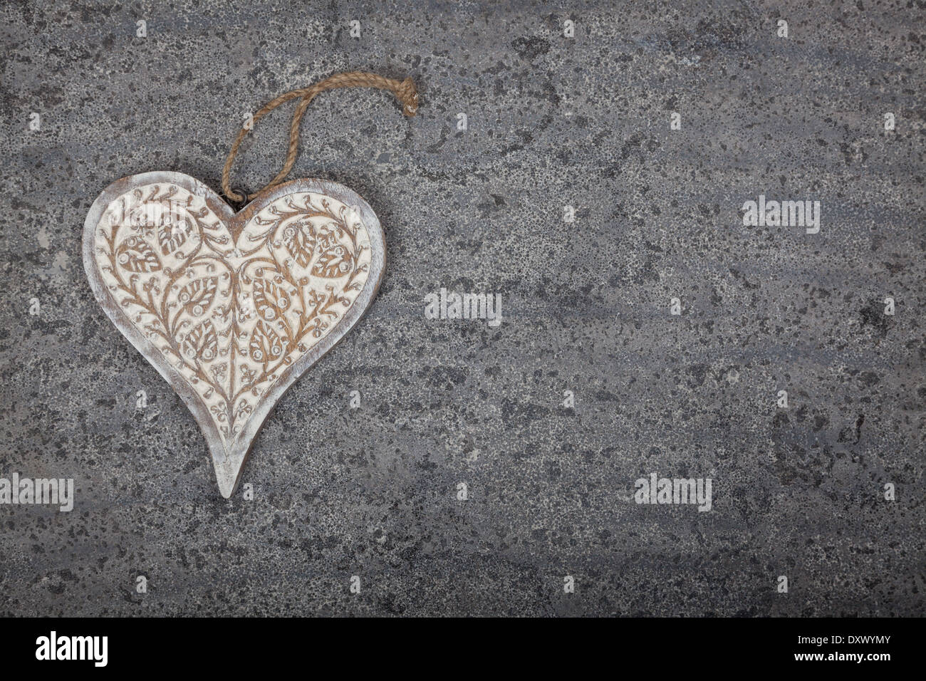 A carved wooden heart on a grey limestone background Stock Photo