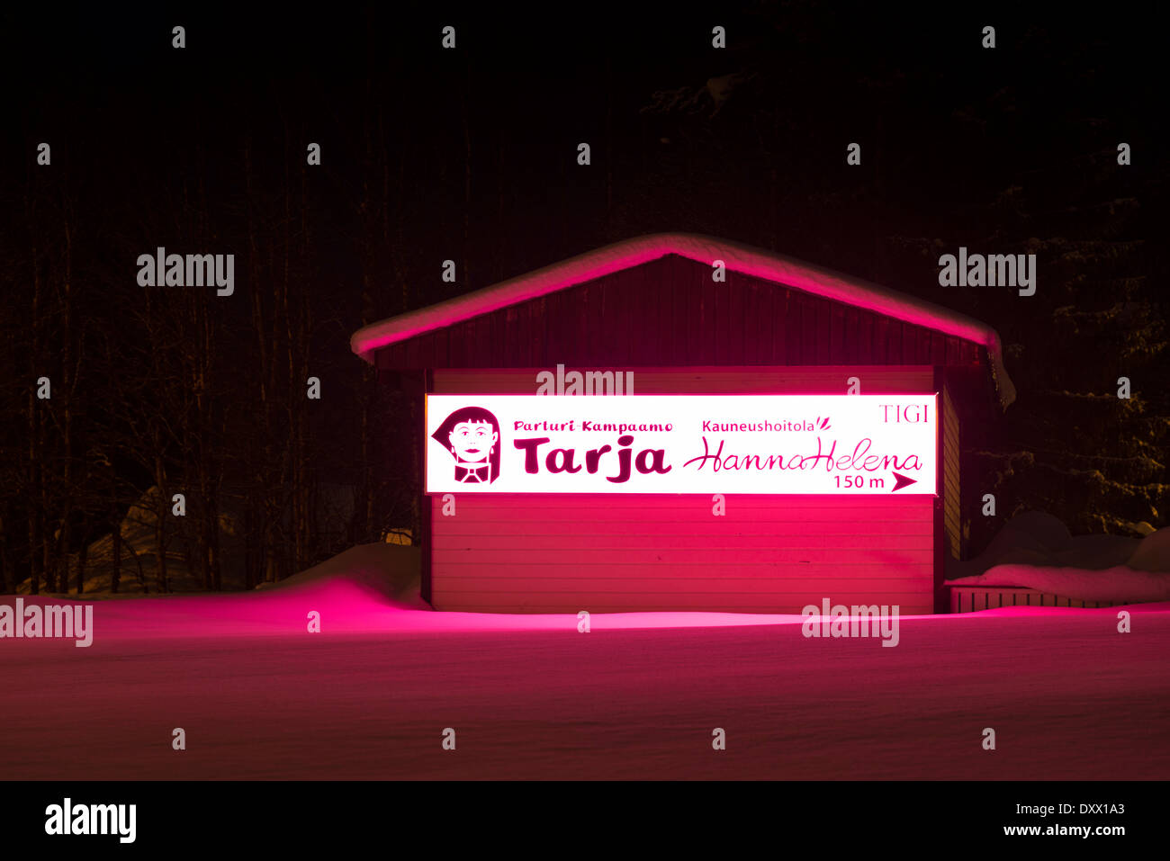 A beauty salon lit up with vivid pink lights at night in winter in Akaslompolo Yllas Finland Stock Photo