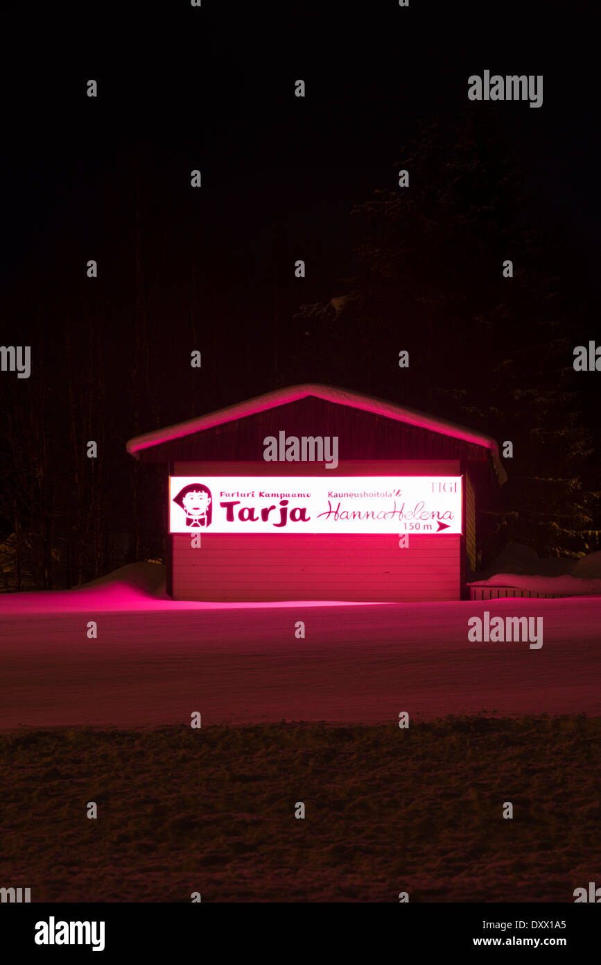 A beauty salon lit up with vivid pink lights at night in winter in Akaslompolo Yllas Finland Stock Photo