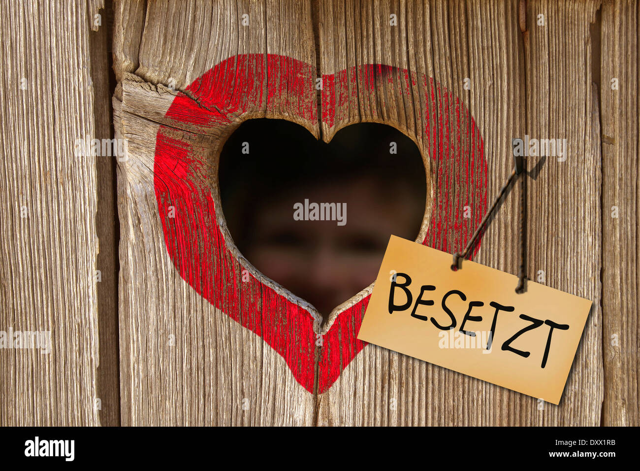 Sign 'Besetzt', German for 'Occupied', next to the heart-shaped hole of a toilet house Stock Photo