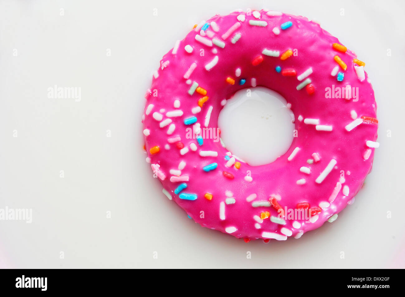 a donut coated with a pink frosting and sprinkles of different colors
