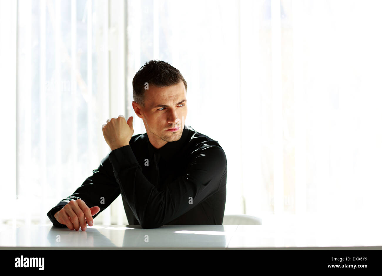 Thoughtful businessman sitting at the table and looking away Stock Photo