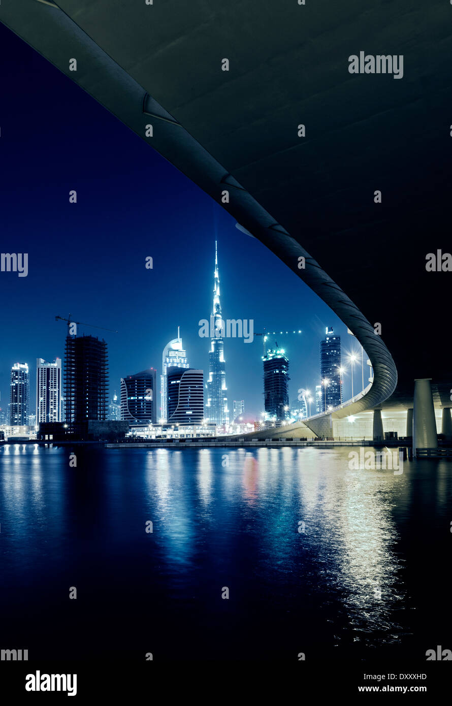 Night view of skyline of new Business Bay District towards Burj Khalifa tower from The Creek river in Dubai United Arab Emirates Stock Photo