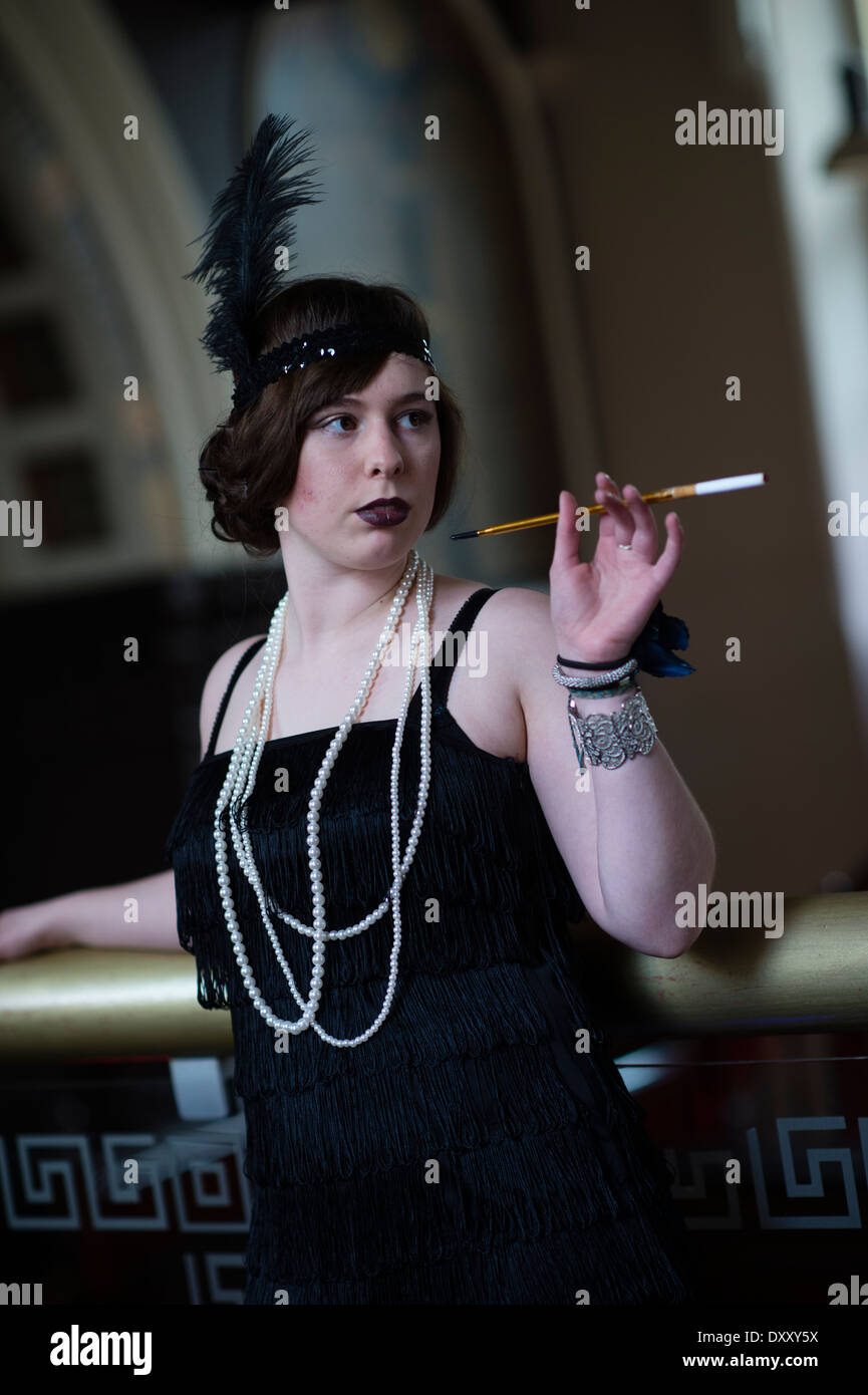 Young women woman girl dressed as a flapper holding cigarette modeling for a 'Great Gatsby' themed makeover photo shoot, UK Stock Photo