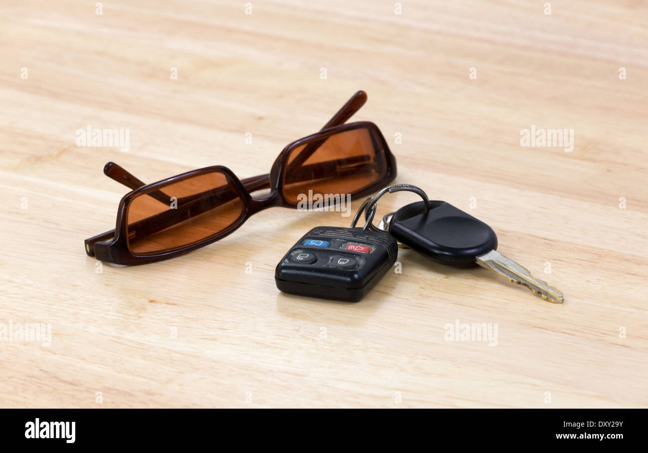 A set of car keys with a pair of sunglasses on a wood countertop. Stock Photo