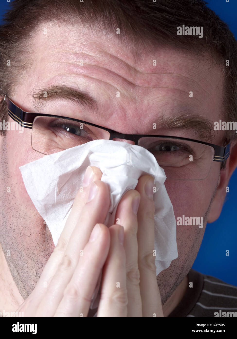 Young man blowing his nose with paper tissue Stock Photo