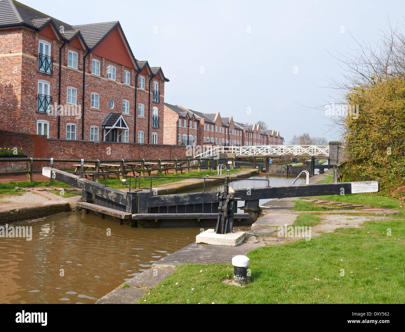 Modern housing on the Trent and Mersey canal with big lock footbridge in Middlewich Cheshire UK Stock Photo