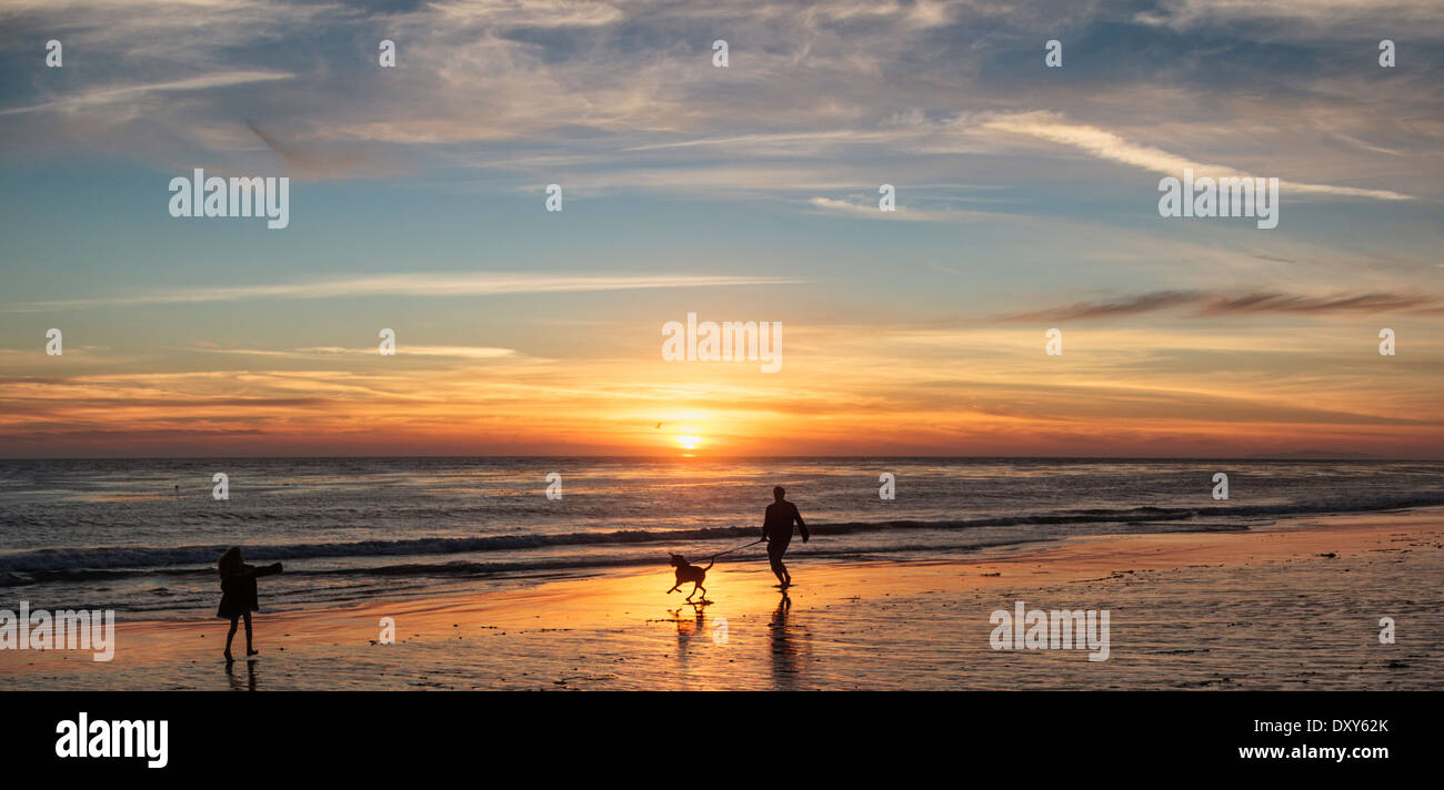 People and dog enjoy  sunset at the dog-friendly area of Leo Carillo State Beach in Southern California Stock Photo