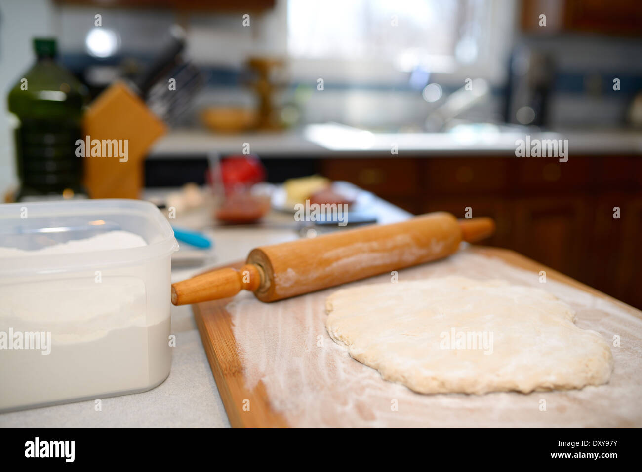 Fresh gluten free dough punched down on a floured board with rolling pin for making a home made pizza Stock Photo