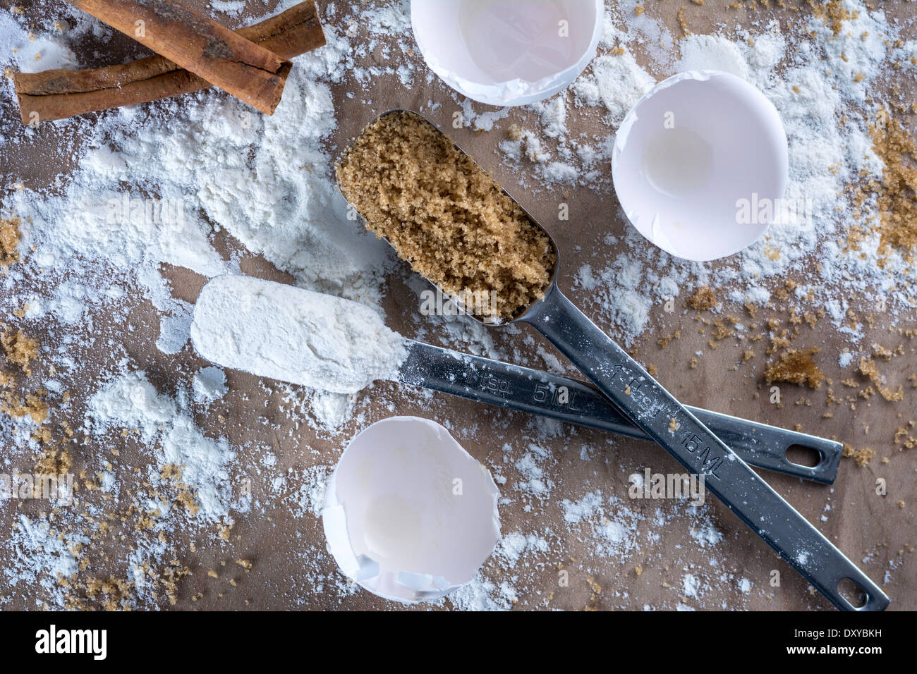 Baker's countertop with broken eggshells, flour, brown sugar and cinnamon sticks Stock Photo