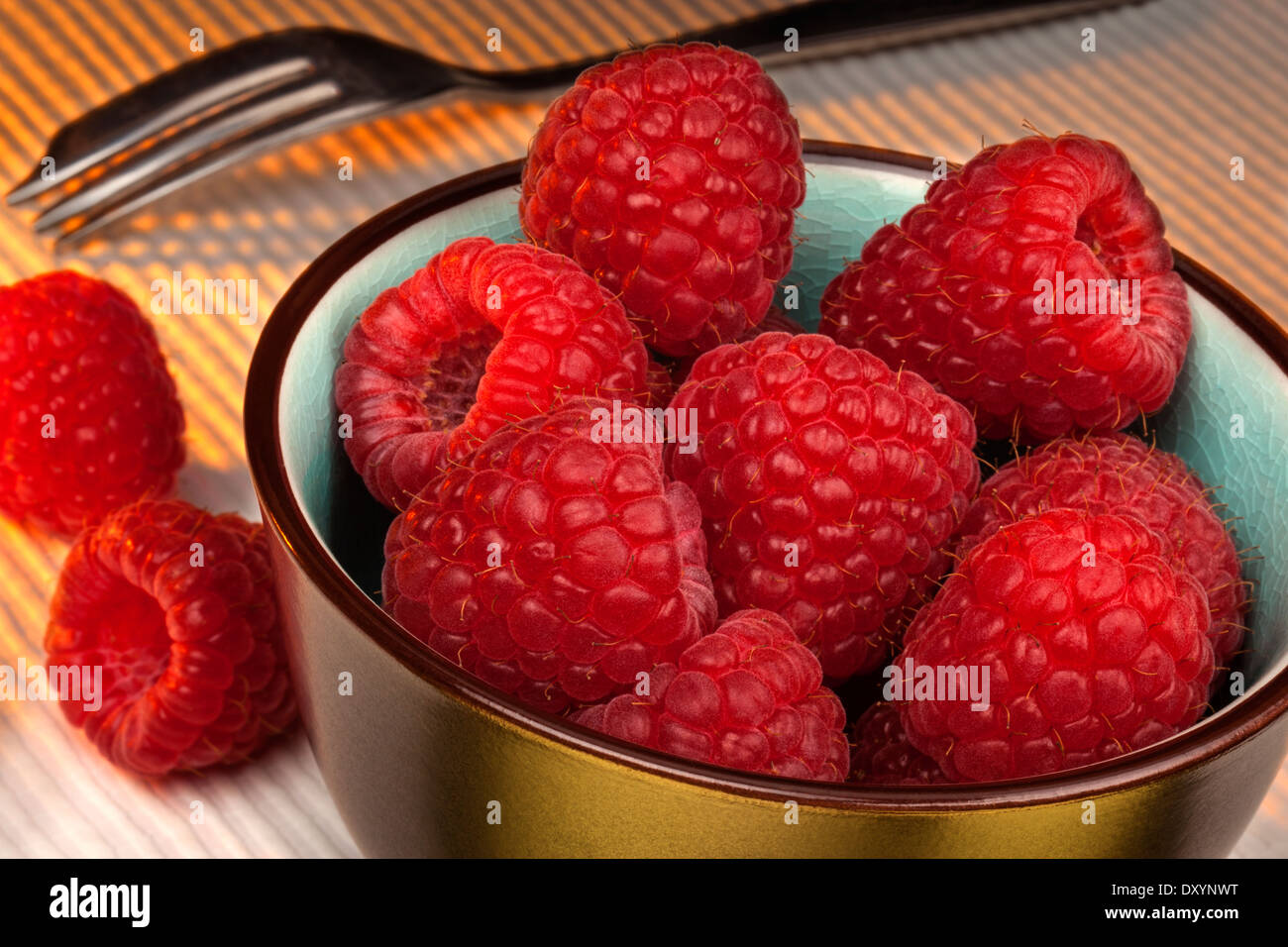 Raspberries are an edible soft fruit related to the blackberry, consisting of a cluster of reddish-pink drupelets. Stock Photo