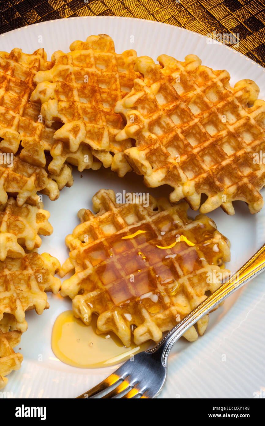 Waffles are mall crisp batter cake, baked in a waffle iron and eaten hot with butter or syrup. Stock Photo