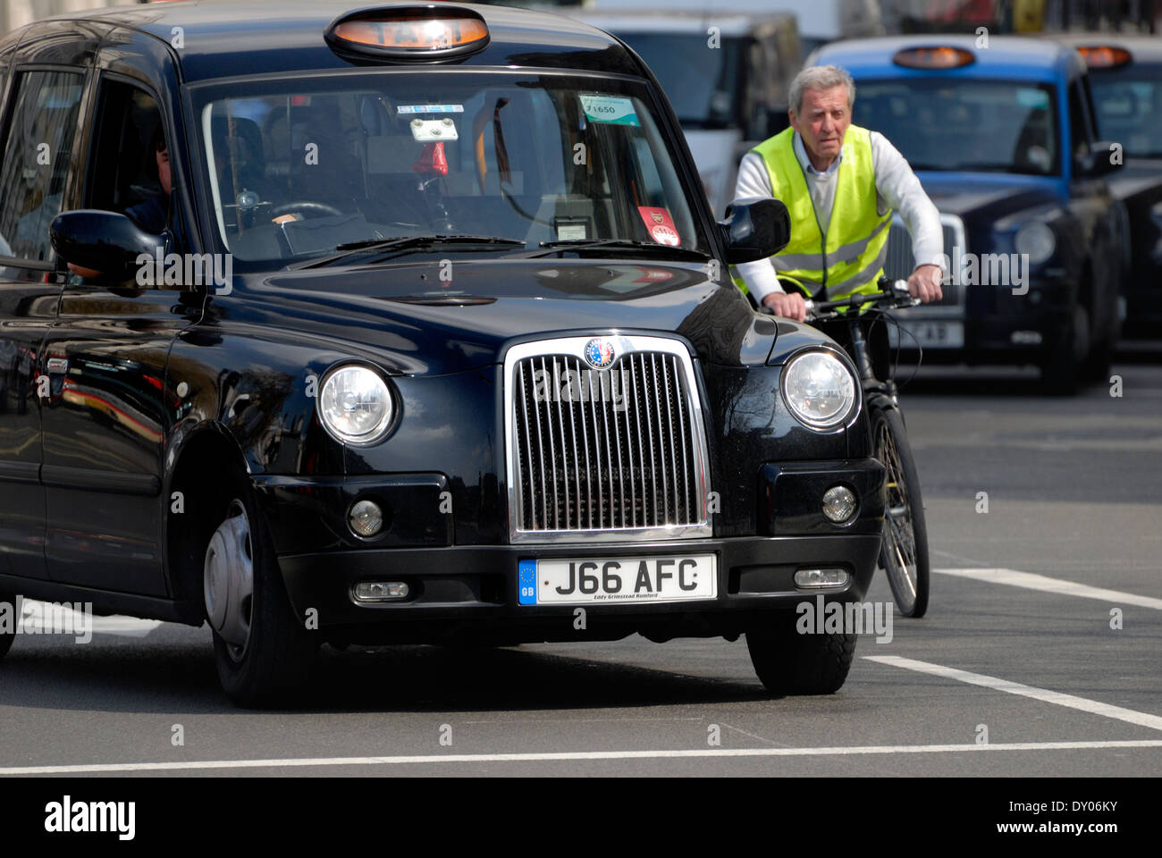 London, England, UK. Black taxi cab and cyclist Stock Photo