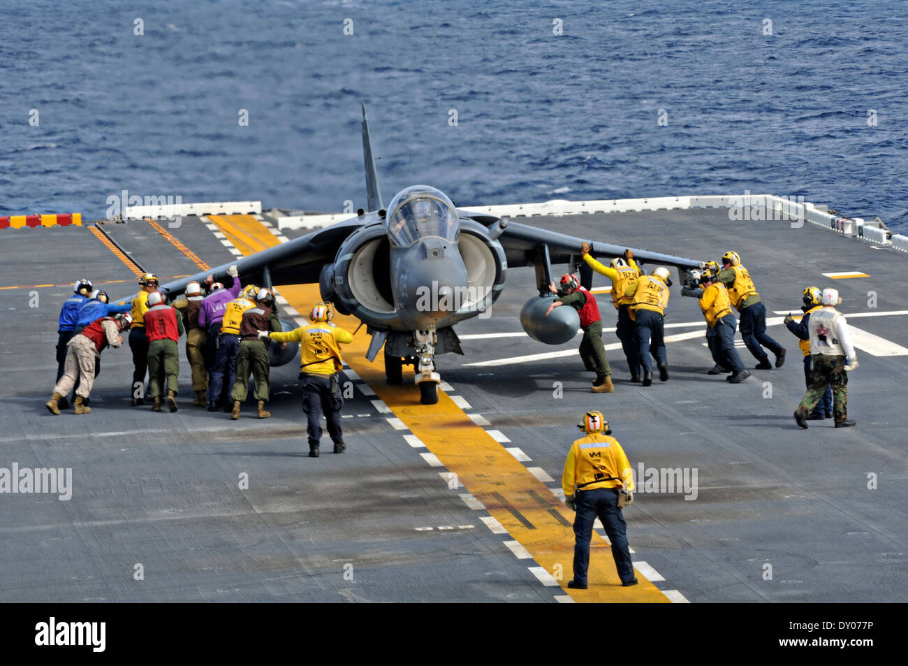 US Sailors and Marines move an AV8B Harrier aircraft into position on