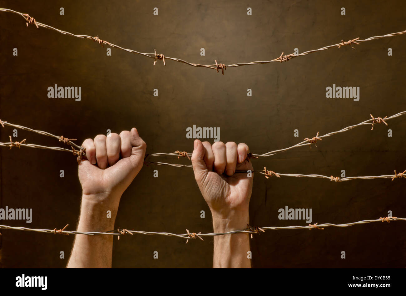 hand behind barbed wire with dark background Stock Photo